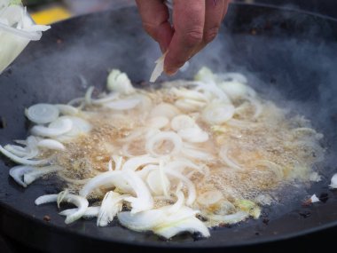 Soğanlar büyük bir saj kızartma tavasında kızartılıyor. Aile pikniği için bir tabak. Lezzetli bir sıcak yemek için malzemeler.