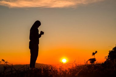Din, ibadet, dua ve övgü kavramında elleri havada bir kadının silueti.