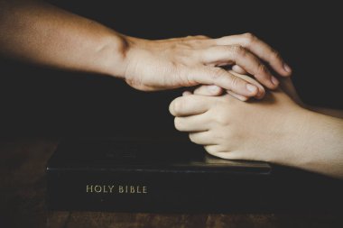 Hands folded in prayer on a Holy Bible in church concept for faith, spirituality and religion, woman praying on holy bible in the morning. woman hand with Bible praying. clipart
