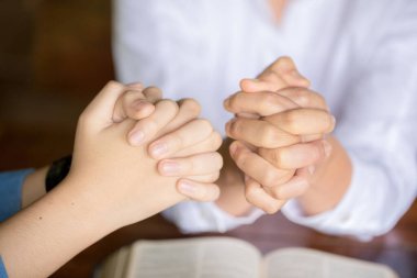 İki kadın birlikte dua ediyor ve birbirlerini cesaretlendiriyorlar. İncil 'e dua eden kadın eli.