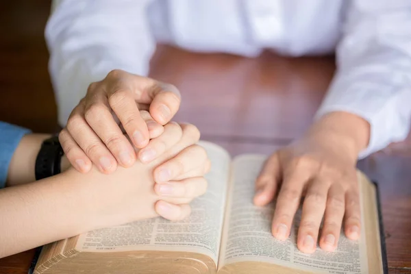 Hands folded in prayer on a Holy Bible in church concept for faith, spirituality and religion, woman praying on holy bible in the morning. woman hand with Bible praying.