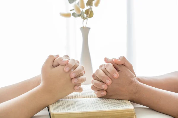 Hands folded in prayer on a Holy Bible in church concept for faith, spirituality and religion, woman praying on holy bible in the morning. woman hand with Bible praying.