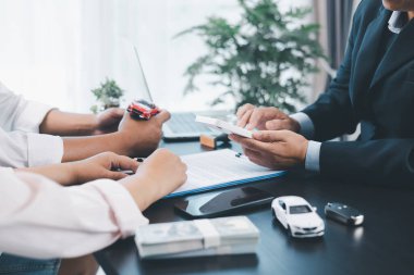 İş adamı araba kredisini hesap makinesiyle açıklıyor, müşteri ofis masasında oyuncak araba ve belgelerle otomobil finansmanı anlaşmasını tartışıyor, araç kredisi, sigorta veya araba kiralama kavramını anlatıyor. araba kredisi.