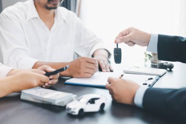 Müşteri, sözleşme imzaladıktan sonra satıcıdan araba anahtarı, ofis masasında başarılı bir otomobil satın alma ve finans anlaşması, araç kredisi, kiralama, sigorta veya mülkiyet konsepti alıyor. araç kredisi.