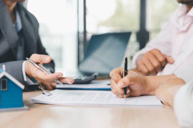 İş adamlarının masa başında kalem ve evrak işleriyle kredi sözleşmesi imzalaması, modern ofis ortamında dizüstü bilgisayar ve hesap makinesi ile finansal anlaşma konsepti. kredi sözleşmesi.