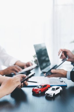 Araba kredisi memuru, nakit, hesap makinesi, anahtar ve oyuncak arabalı müşteriye, otomobil finansmanı, kiralama, sigorta, ödeme planı ve iş sözleşmesi konseptini açıklıyor. araba kredisi.