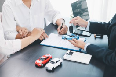 Müşteri, sözleşme imzaladıktan sonra satıcıdan araba anahtarı, ofis masasında başarılı bir otomobil satın alma ve finans anlaşması, araç kredisi, kiralama, sigorta veya mülkiyet konsepti alıyor. araç kredisi.