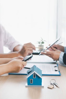 Ev modeli, arka planda sözleşme, emlak yatırımı konsepti, ipotek kredisi, ev sahipliği, gayrimenkul ticareti ve mali anlaşma konularını tartışan bulanık insanlarla birlikte masada..