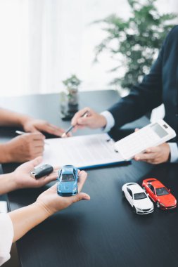 İş adamı araba kredisini hesap makinesiyle açıklıyor, müşteri ofis masasında oyuncak araba ve belgelerle otomobil finansmanı anlaşmasını tartışıyor, araç kredisi, sigorta veya araba kiralama kavramını anlatıyor. araba kredisi.