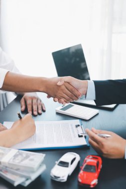 Araba kredisi sözleşmesini imzaladıktan sonra iş tokalaşması, para, hesap makinesi ve araç modeli ile güven ve başarılı otomobil finans anlaşmasının sembolü, anlaşma ve ortaklık kavramı. araba kredisi.
