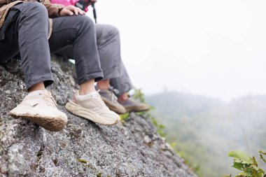 Yürüyüş ayakkabılarıyla kayalık kayalıklarda dinlenen, maceranın sembolü, açık hava yaşam tarzı, meydan okuma, keşif, kararlılık, doğa yolculuğu ve dağ yolculuğundaki özgürlük..
