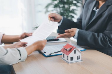 Ev modeli, arka planda sözleşme, emlak yatırımı konsepti, ipotek kredisi, ev sahipliği, gayrimenkul ticareti ve mali anlaşma konularını tartışan bulanık insanlarla birlikte masada..