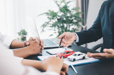 Araba kredisi memuru, nakit, hesap makinesi, anahtar ve oyuncak arabalı müşteriye, otomobil finansmanı, kiralama, sigorta, ödeme planı ve iş sözleşmesi konseptini açıklıyor. araba kredisi.