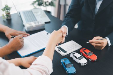 Araba kredisi sözleşmesini imzaladıktan sonra iş tokalaşması, para, hesap makinesi ve araç modeli ile güven ve başarılı otomobil finans anlaşmasının sembolü, anlaşma ve ortaklık kavramı. araba kredisi.