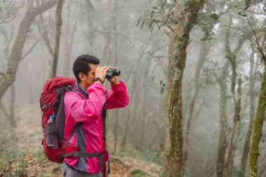 Sisli ormanda dürbün kullanan gezgin, maceranın sembolü, keşif, keşif, açık hava yaşam tarzı, yürüyüş yolculuğu, merak ve doğada seyahat için ilham..