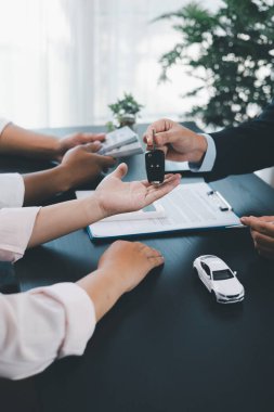 Müşteri, sözleşme imzaladıktan sonra satıcıdan araba anahtarı, ofis masasında başarılı bir otomobil satın alma ve finans anlaşması, araç kredisi, kiralama, sigorta veya mülkiyet konsepti alıyor. araç kredisi.