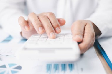 Mali analiz ve muhasebe masasında hesap makinesi kullanarak rapor ve çizelge hazırlayan iş kadınını kapatın. İş planlama, bütçe hesaplama ve yatırım stratejisi kavramı.