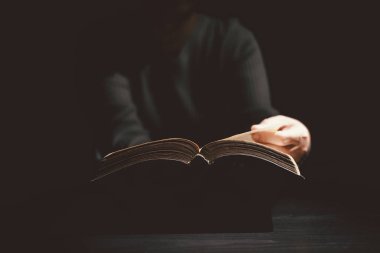 El ele tutuşup İncil 'i karanlığın içinde dramatik bir ışık altında sunarak Hıristiyanlığı, inancı, İncil' i, ibadeti ve umudu sembolize ediyor. Tanrı 'nın Sözü kavramı hayata ışık getiriyor..