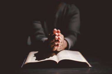 Elleri kutsal İncil 'in üzerine katlanmış, inancı, bağlılığı, Hristiyanlığı, umudu ve manevi gücü simgeleyen dualar. İbadet, meditasyon ve Tanrı 'ya güvenme kavramı..