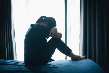 Stresli bir kadın karanlık bir odada tek başına oturuyor, başını eğiyor, depresyonu, endişeyi, umutsuzluğu, yalnızlığı, zihinsel sağlık mücadelesini, tükenmiş ve duygusal acıyı simgeliyor..