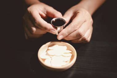 Ahşap bir kâse ve şarap kadehiyle komünyon ekmeğini tutan eller, Kutsal Komünyonu, Ayini, İsa 'nın kurban edilmesini ve Hristiyan inancının Lord Supper' a olan bağlılığını simgeliyor..