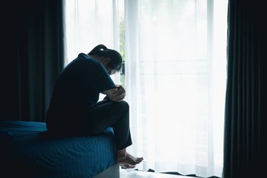 Stresli bir kadın karanlık bir odada tek başına oturuyor, başını eğiyor, depresyonu, endişeyi, umutsuzluğu, yalnızlığı, zihinsel sağlık mücadelesini, tükenmiş ve duygusal acıyı simgeliyor..