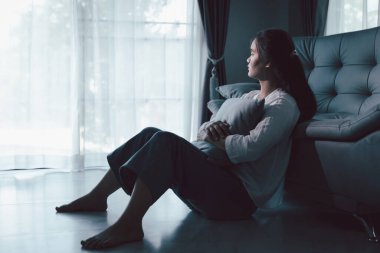 Evdeki kanepede oturan umutsuz, yorgun kız. Genç kadın oturma odasında oturuyor, üzgün ve depresif hissediyor. Psikolojik bir sorun. Depresyon ve yalnızlık kavramı.