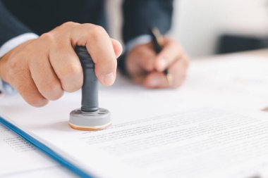 İşadamı resmi belgeleri masasında imzalayıp damgalıyor, yasal sözleşme onayı, yetki belgesi ya da iş anlaşmasının kurumsal arka planda onaylanması. pul onayı