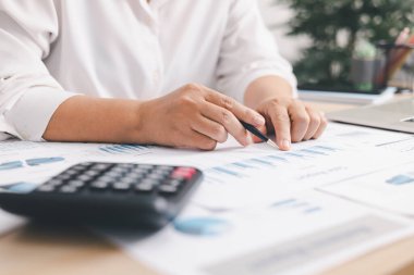 Ofis masasında mali raporlu hesap makinesi ve dizüstü bilgisayar kullanan işadamları, muhasebe analizi, bütçe planlaması, veri yönetimi ve kurumsal finans stratejisi kavramı.