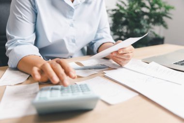 Bir masadaki harcamaları hesaplayan ve makbuzları inceleyen iş adamı, mali planlama, fatura ödemesi, muhasebe iş akışı, bütçe yönetimi, maliyet yönetimi ve günlük ofis finans görevlerini gösteren.