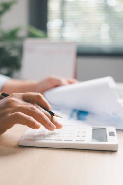 Ofis çalışanı, finansal verileri hesap makinesiyle hesaplarken iş raporlarını gözden geçirir, muhasebe raporlarını inceler, modern işyerindeki verimlilik, verimlilik, mesleki iş akışını hesaplar.