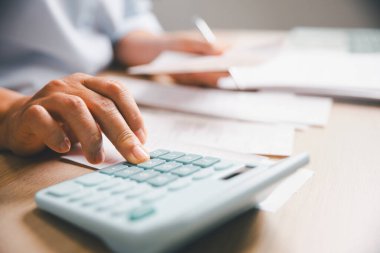 Faturaları, belgeleri, muhasebe görevlerini, bütçe yönetimini, masraf yönetimini, profesyonel mali iş akışını incelerken, mali verileri hesap makinesiyle hesaplayan ofis çalışanının kapatılması.