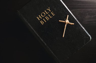 Kutsal İncil küçük ahşap haç, siyah deri kaplamalı. Karanlık dramatik ışık. Hristiyan inancını simgeliyor.