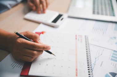 Ofis çalışanı takvimi işaretlerken finansal verileri hesaplar, program planlama, zaman yönetimi, iş görevleri, üretkenlik, modern iş ortamında profesyonel iş akışı.