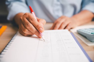 Ofis çalışanlarına yakın çekim, deftere finansal rakamlar yazmak, muhasebe görevlerini resmetmek, kayıt tutmak, gider takibi, bütçe belirleme, işyerinde profesyonel mali yönetim.