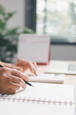 Defterdeki mali kayıtları incelerken, ofis çalışanlarının sayılarla, hesap makineleriyle, hesap makineleriyle, muhasebe görevleriyle, bütçe takibiyle, masraf takibiyle, profesyonel mali yönetimle ilgili bilgileri yakından incelerken..