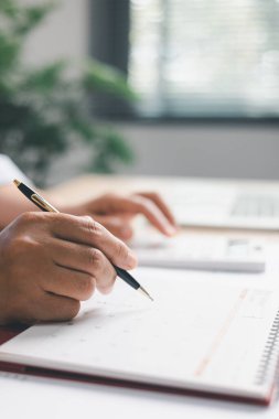 Ofis çalışanı takvimi işaretlerken finansal verileri hesaplar, program planlama, zaman yönetimi, iş görevleri, üretkenlik, modern iş ortamında profesyonel iş akışı.