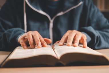 Masanın üzerinde açık bir İncil 'i, sıcak bir iç mekan ışığı ve sığ bir alan derinliğini okurken, Hıristiyan inancını, bağlılığını, çalışmasını ve evdeki ibadetini yansıtırken sessiz bir yansıtmayı,.