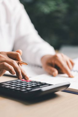 Hesap makinesinin yanındaki bir defterde, bütçe ve muhasebe için el yazısı notları var. Kişisel finans planlaması, gider takibi, vergi hesaplaması, yumuşak odak arkaplanı, kopyalama alanı.