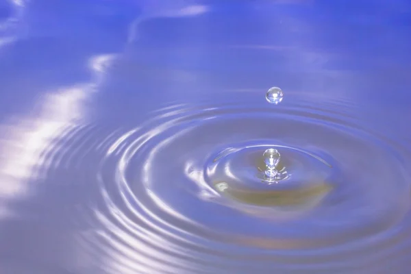 Wassertropfen, die ins Wasser fallen, machen einen perfekten Tropfen Spritzer. — Stockfoto