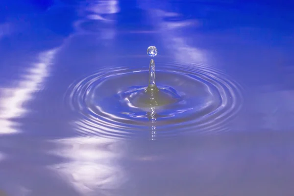 Wassertropfen, die ins Wasser fallen, machen einen perfekten Tropfen Spritzer. — Stockfoto