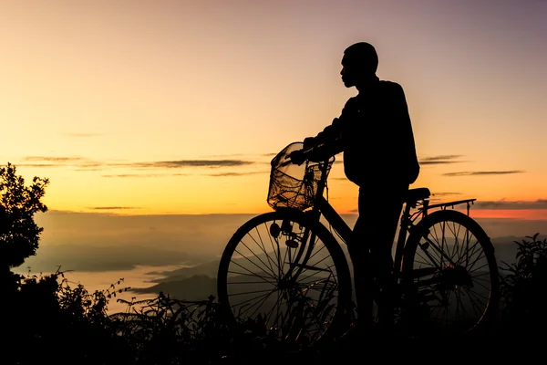 Chłopiec jazdy na rowerze na tle wschód słońca. Sylwetka — Zdjęcie stockowe