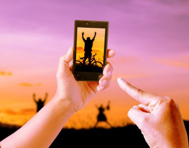 Gün batımı, siluet, özgürlük ve mutluluk bulanıklık doğa arka planda cep telefonu ile oynarken resimler lchildren alarak.