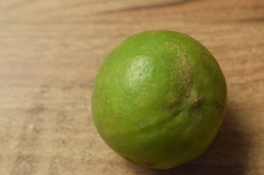 Doğal yeşil limonlar, ahşap arka planda izole edilmiş, yakın plan.