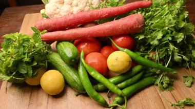 Masadaki organik sebzeler, domatesler, limonlar, havuçlar, maydanozlar, salatalıklar, yeşil biberler.