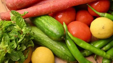 Masadaki organik sebzeler, domatesler, limonlar, havuçlar, maydanozlar, salatalıklar, yeşil biberler.