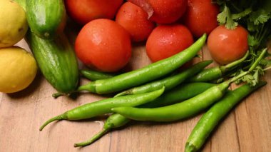 Masadaki organik sebzeler, domatesler, limonlar, havuçlar, maydanozlar, salatalıklar, yeşil biberler.