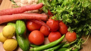 Masadaki organik sebzeler, domatesler, limonlar, havuçlar, maydanozlar, salatalıklar, yeşil biberler.