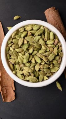 Siyah Arkaplan Dönen Dikey Görüntü Üzerine Tarçın Çubukları (Dalchini) ile Beyaz Bowling 'de Kakule (Elechi) Üst Görünümü