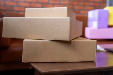 Oturma odasında teslim edilecek karton kutu paketi. Evden çalışmak ve küçük işletme kavramı.